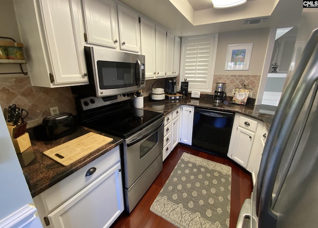 kitchen featuring stainless steel appliances, visible vents, white cabinets, decorative backsplash, and dark wood-style floors