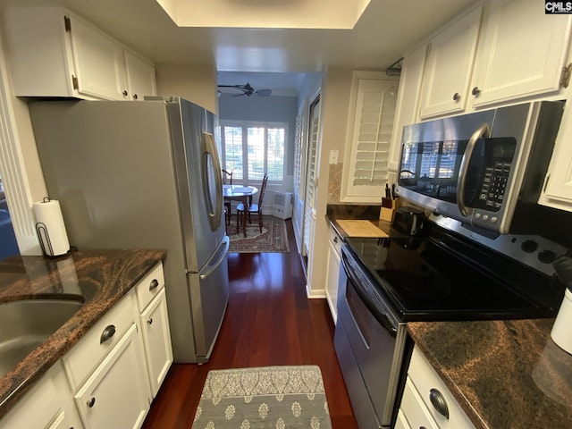 kitchen with dark wood-style floors, appliances with stainless steel finishes, dark stone counters, and white cabinetry