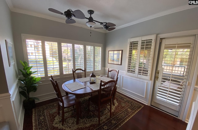 dining room featuring a ceiling fan, wainscoting, crown molding, and wood finished floors