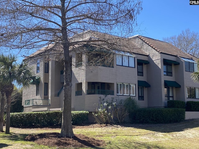 view of side of home with a tiled roof and stucco siding