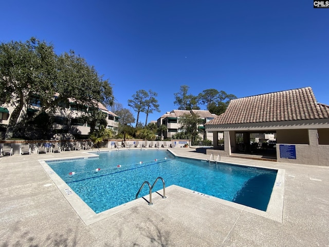 community pool with a patio and fence