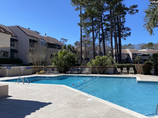 community pool featuring a patio, fence, and a residential view