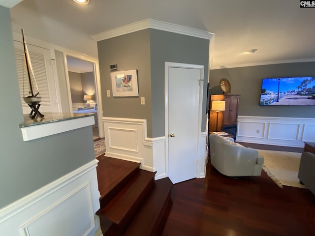 staircase featuring a wainscoted wall, crown molding, a decorative wall, and wood finished floors