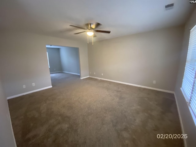 empty room with ceiling fan, baseboards, and dark colored carpet