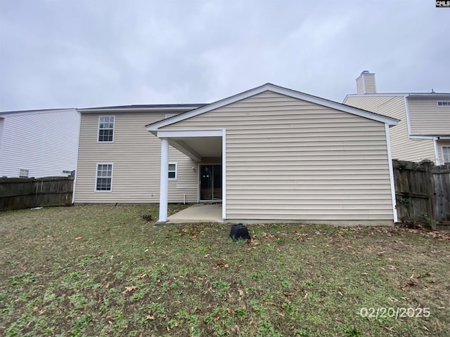 back of property featuring a patio area, a lawn, and fence