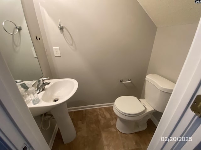 half bathroom featuring baseboards, a textured ceiling, and toilet