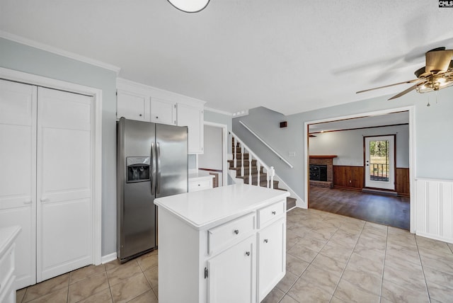 kitchen with a wainscoted wall, light countertops, a fireplace, white cabinetry, and stainless steel refrigerator with ice dispenser