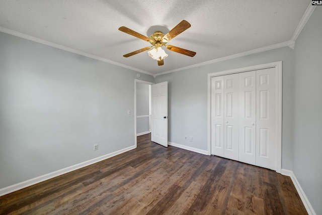 unfurnished bedroom with a closet, dark wood-style flooring, crown molding, and baseboards