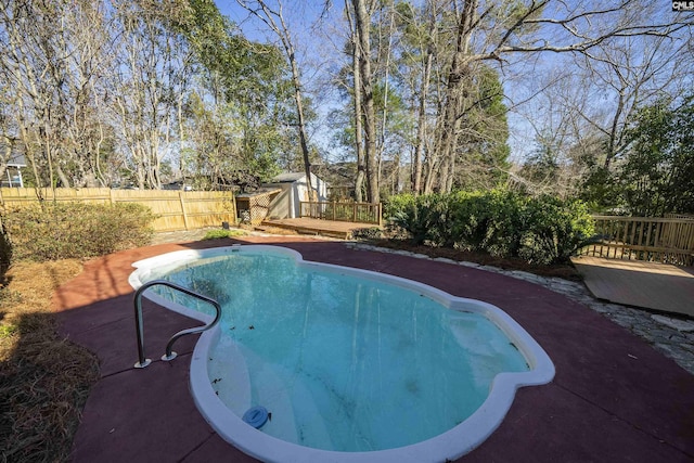 view of swimming pool with an outdoor structure, fence, and a wooden deck