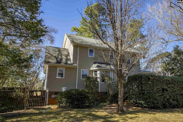 rear view of house with crawl space, fence, and a lawn