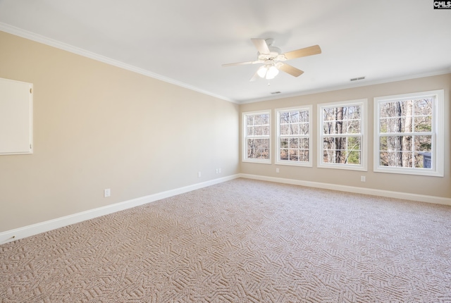 carpeted spare room with baseboards, ceiling fan, visible vents, and crown molding