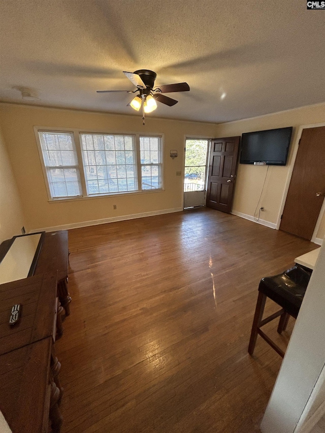 living area featuring ceiling fan, a textured ceiling, baseboards, and dark wood-style flooring