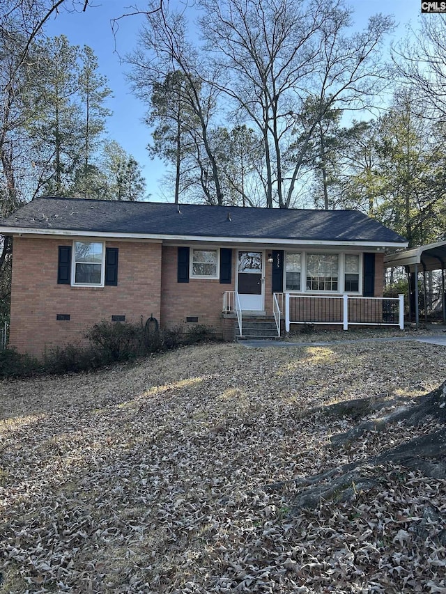 ranch-style home featuring a shingled roof, crawl space, covered porch, a carport, and brick siding