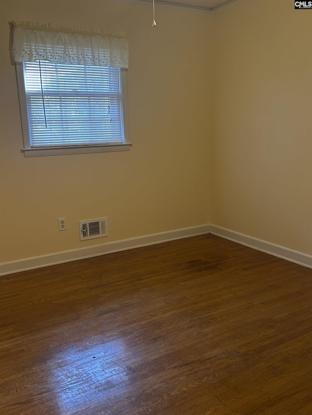 spare room with visible vents, dark wood finished floors, and baseboards