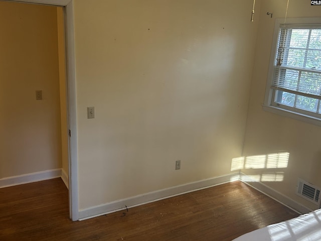 empty room with visible vents, baseboards, and wood finished floors