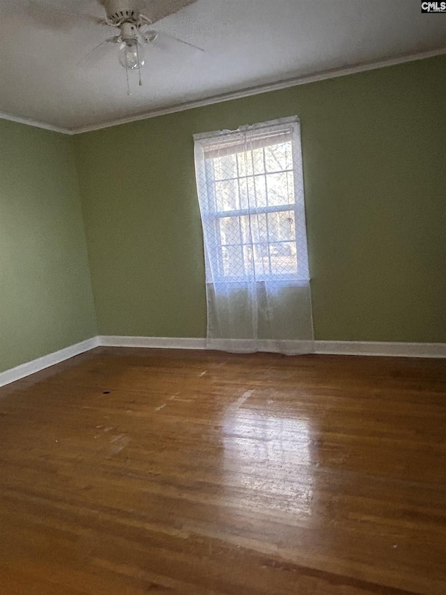 unfurnished room featuring crown molding, baseboards, and wood finished floors