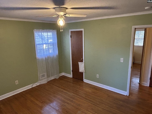 spare room with a healthy amount of sunlight, visible vents, wood finished floors, and ornamental molding