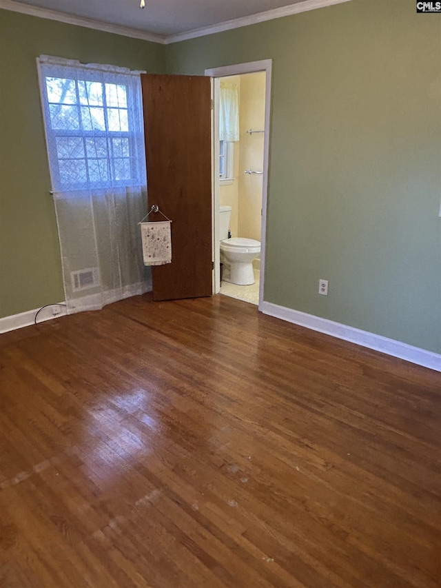 unfurnished bedroom with visible vents, baseboards, ensuite bath, wood finished floors, and crown molding