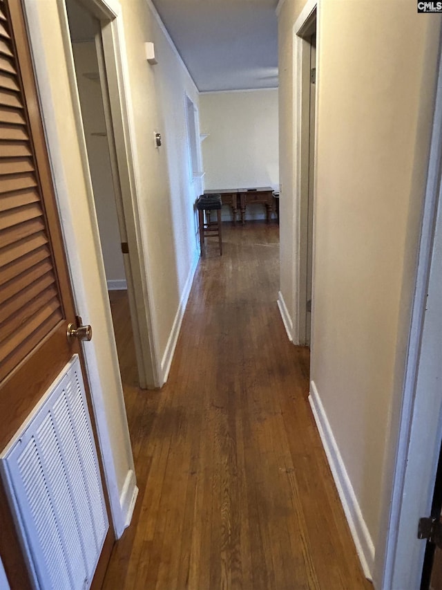 corridor featuring baseboards, visible vents, and dark wood-style flooring