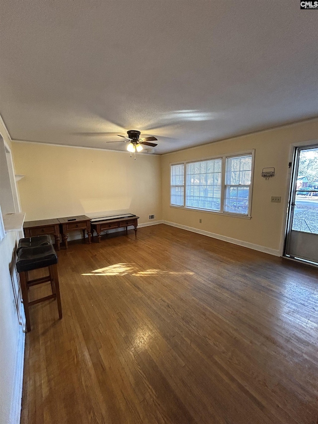 unfurnished living room featuring a textured ceiling, dark wood-type flooring, plenty of natural light, and baseboards