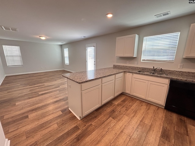 kitchen with light stone counters, a sink, visible vents, light wood-type flooring, and dishwasher