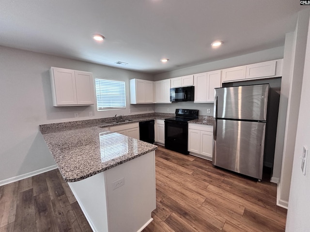 kitchen featuring a peninsula, a sink, white cabinets, dark wood-style floors, and black appliances