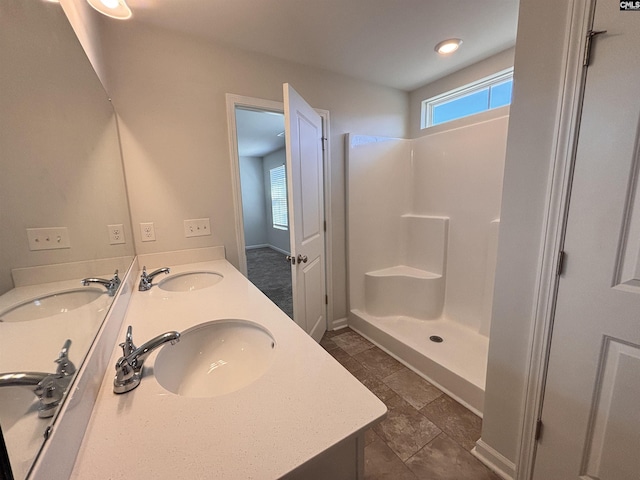 bathroom with double vanity, a walk in shower, and a sink