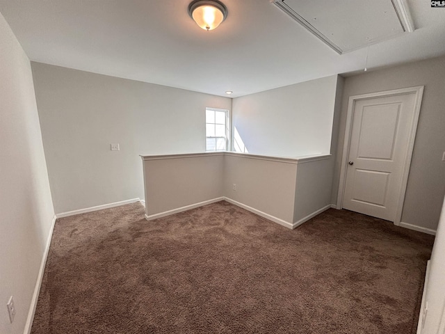 empty room with carpet, attic access, and baseboards