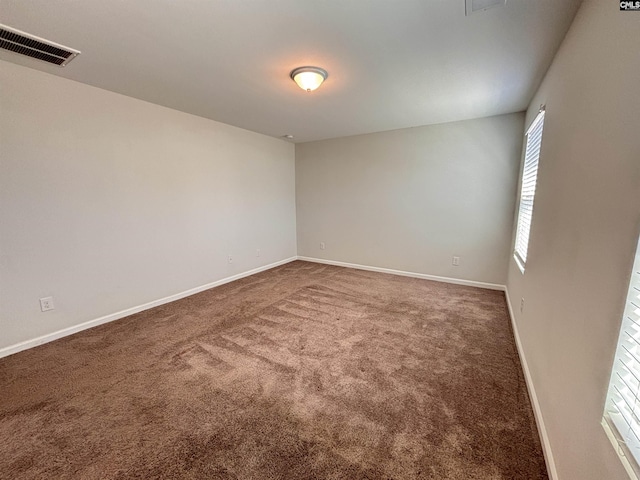 carpeted empty room featuring visible vents and baseboards