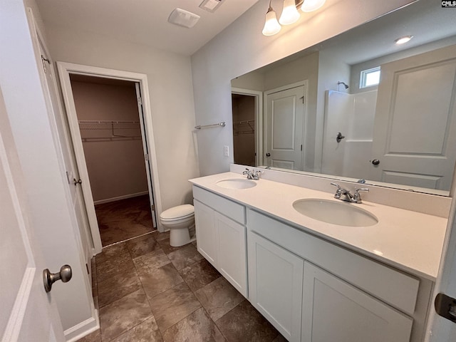 bathroom with double vanity, toilet, walk in shower, and a sink