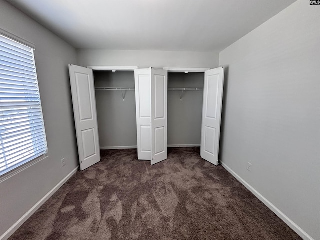 unfurnished bedroom with multiple closets, carpet, and baseboards