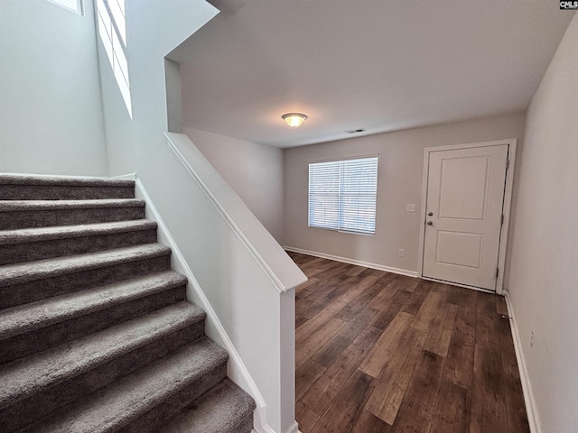 stairs with wood finished floors, visible vents, and baseboards