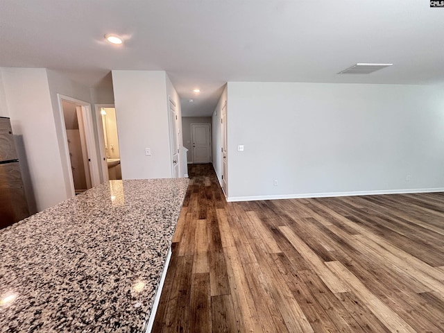 interior space with stone counters, recessed lighting, dark wood-type flooring, visible vents, and baseboards