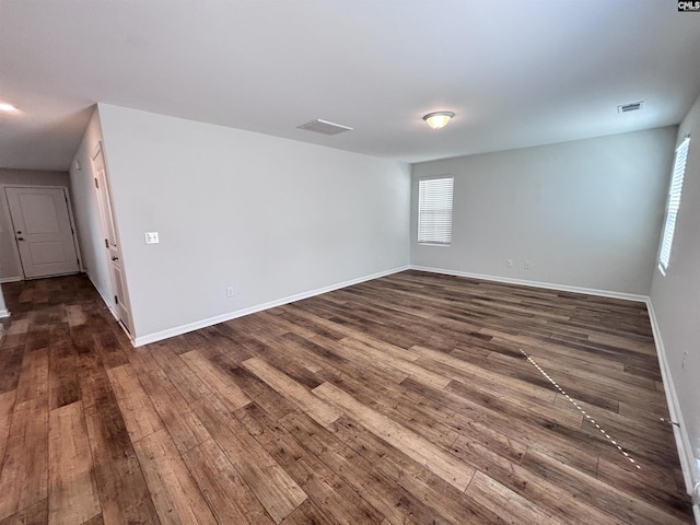 spare room featuring dark wood-style floors, baseboards, and visible vents