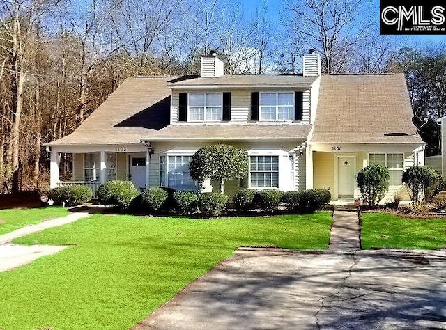 view of front of house with a porch, a chimney, and a front lawn