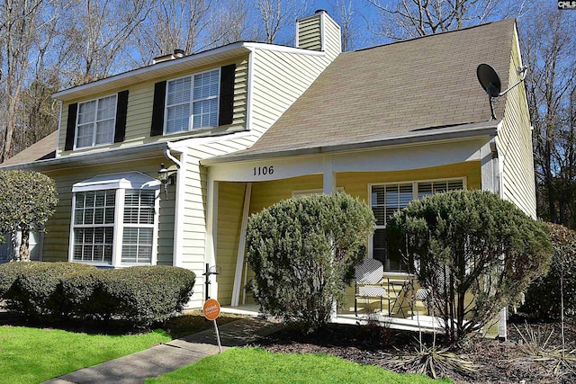 view of front facade with covered porch and a chimney