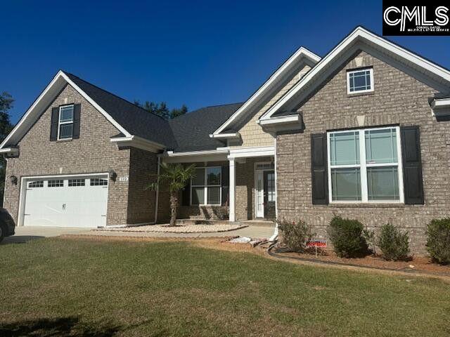 craftsman inspired home with a front lawn, an attached garage, and brick siding