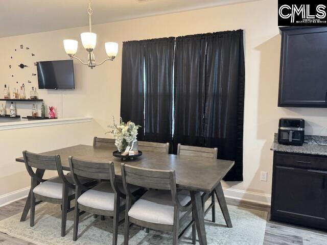 dining room with a notable chandelier, wood finished floors, and baseboards