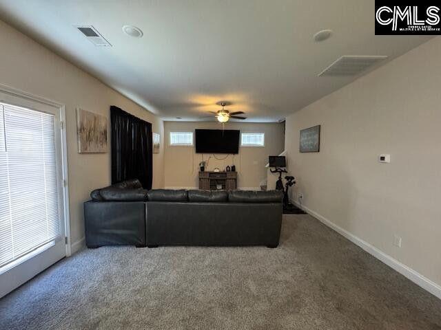 carpeted living room featuring a ceiling fan, visible vents, and baseboards