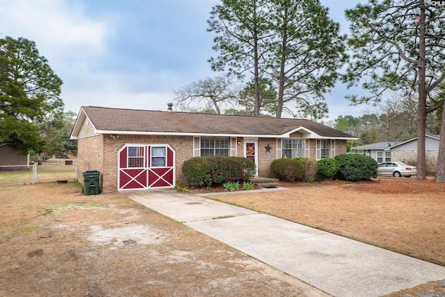 single story home featuring brick siding, fence, and roof with shingles