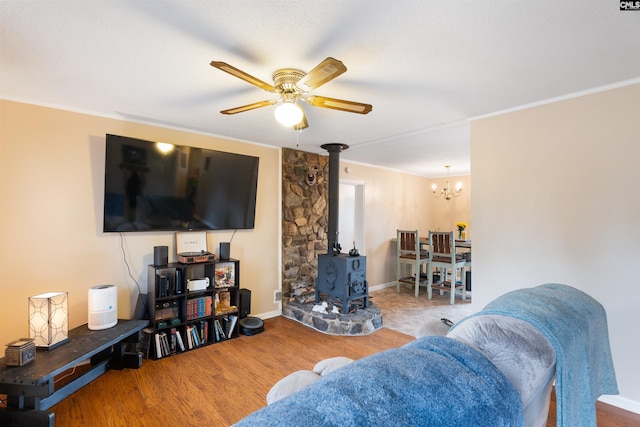 living area featuring ornamental molding, a wood stove, ceiling fan, and wood finished floors