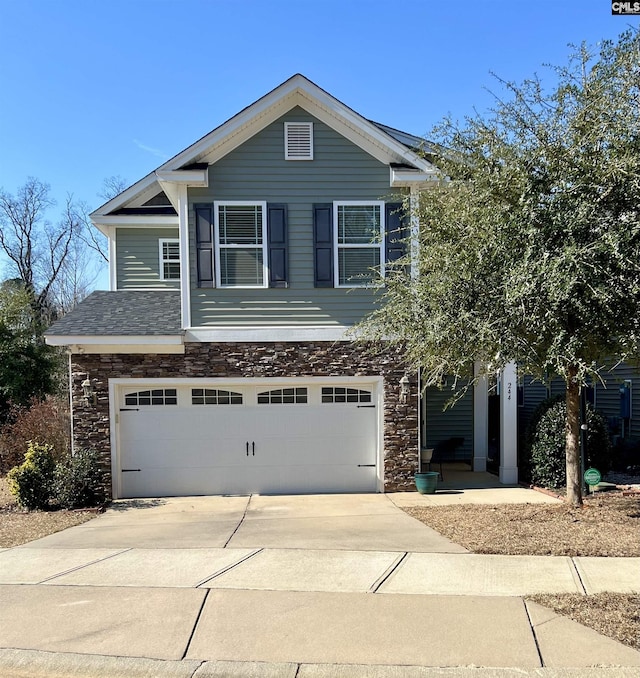 view of front facade featuring stone siding, an attached garage, and driveway