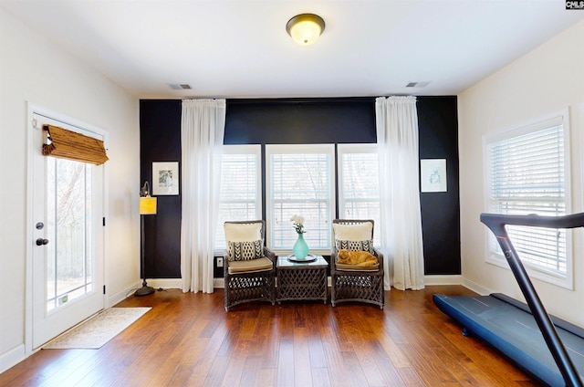 living area with visible vents, a wealth of natural light, and hardwood / wood-style flooring