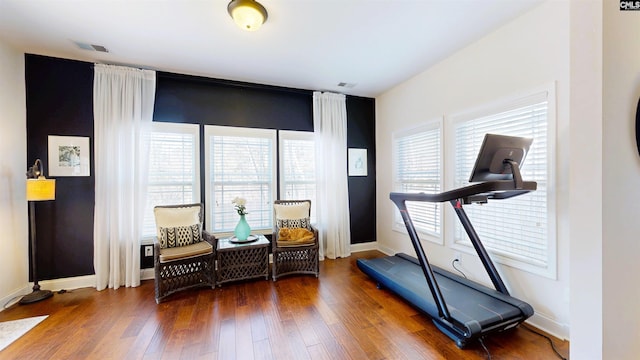 exercise room with wood-type flooring, visible vents, and baseboards