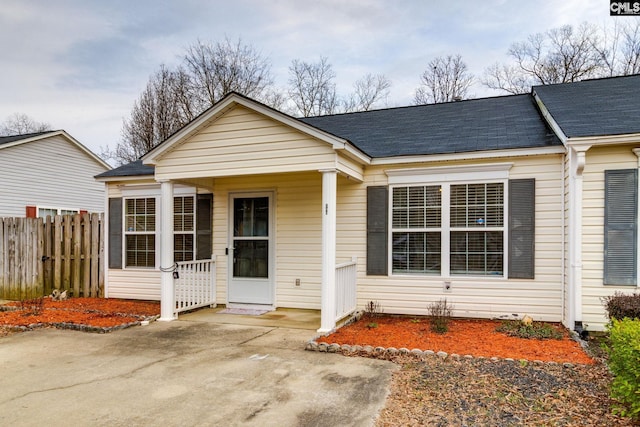 bungalow featuring a porch, roof with shingles, and fence