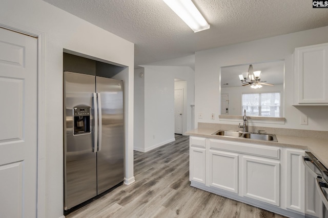 kitchen featuring white cabinets, appliances with stainless steel finishes, light countertops, light wood-type flooring, and a sink