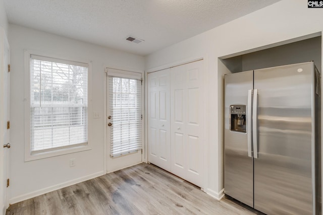 entryway with light wood-style floors, visible vents, a textured ceiling, and baseboards