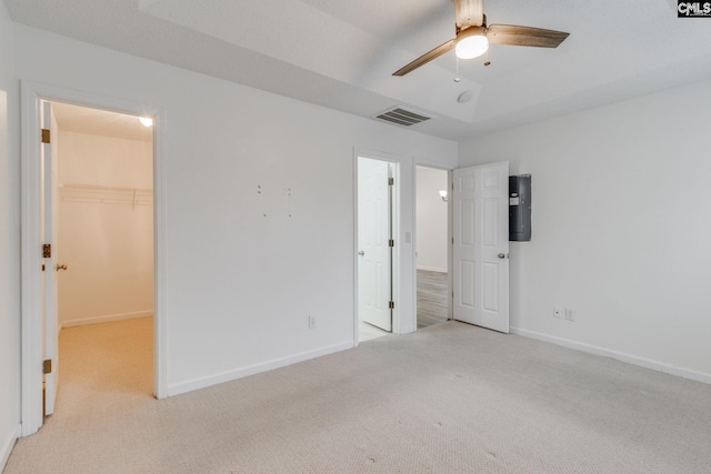 unfurnished bedroom featuring light colored carpet, visible vents, baseboards, a spacious closet, and a raised ceiling