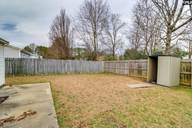 view of yard featuring a storage shed, a fenced backyard, a patio area, and an outbuilding