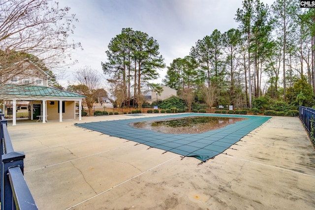 pool with a patio area and fence